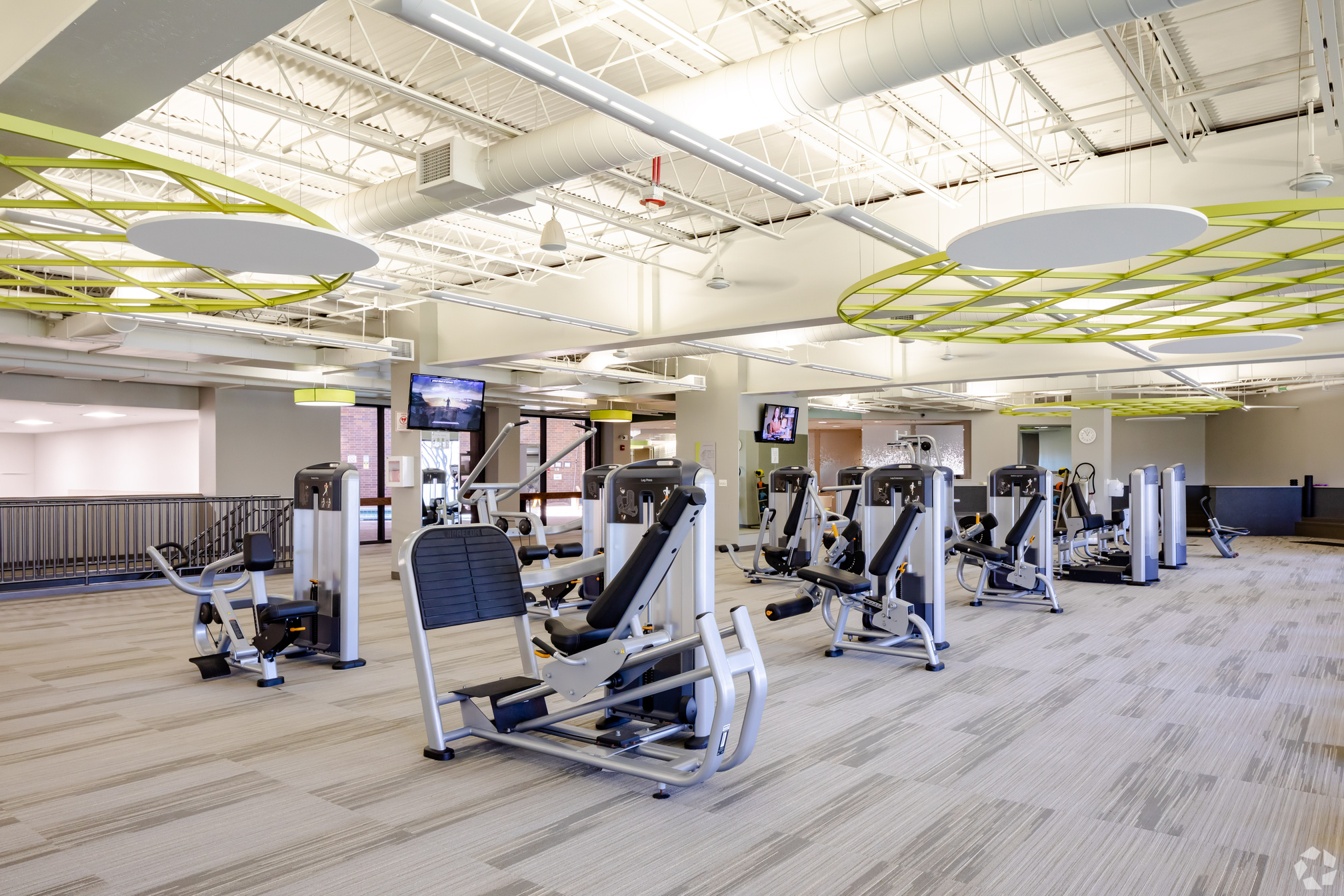 a gym room with exercise machines and televisions